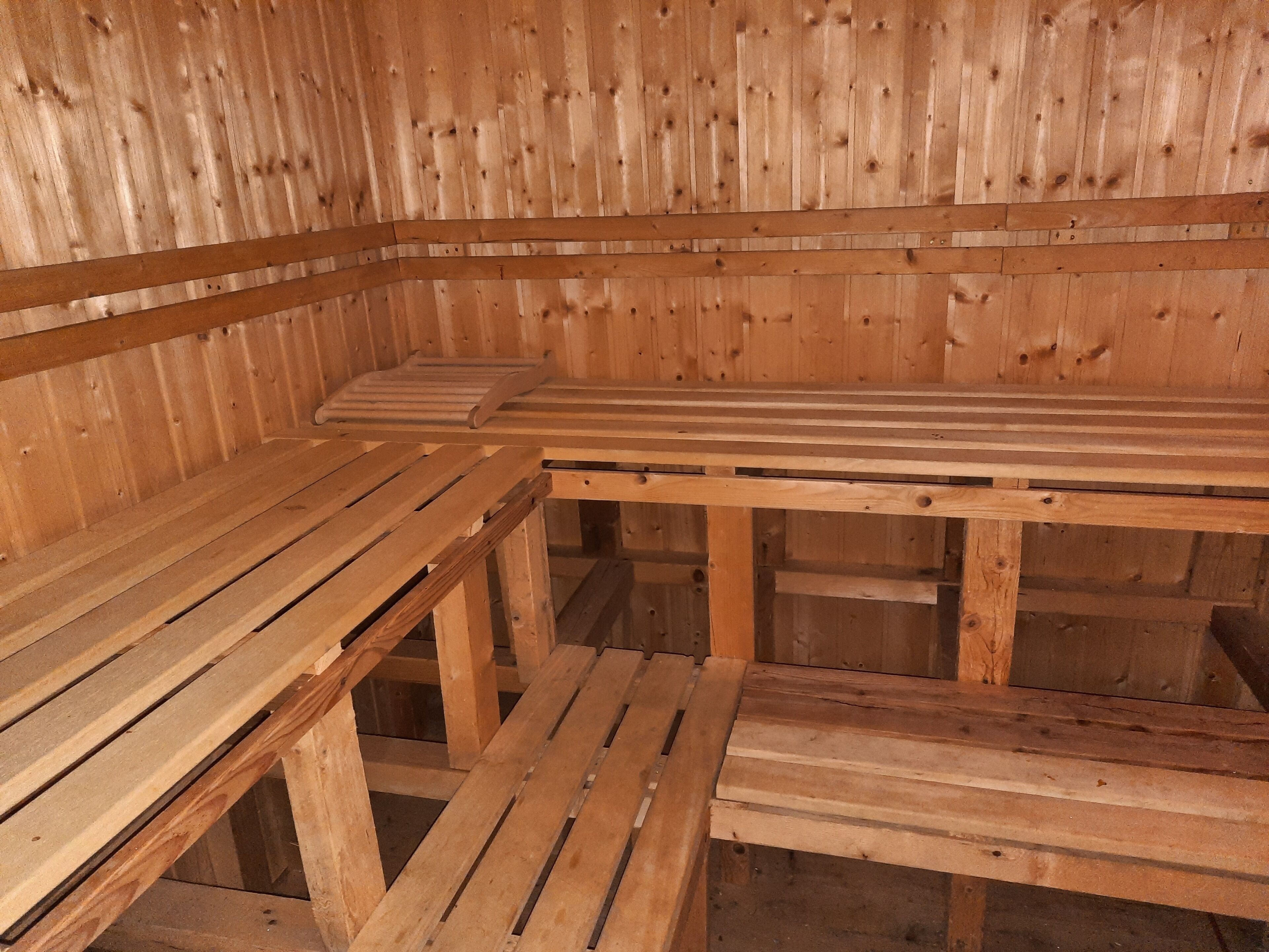 Eine Sauna mit Holzbänken und schräg versiegelter Decke.
