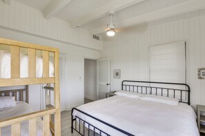 A bedroom with a bunk bed, a single bed, white walls, a ceiling fan, and a door leading to another room. - Casa Del Mare | Beach to Bay on Alligator Point (Alligator Point)