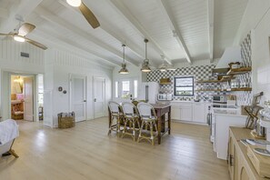 A spacious kitchen with white cabinetry, a wooden dining table with four chairs, and a ceiling fan. - Casa Del Mare | Beach to Bay on Alligator Point (Alligator Point)