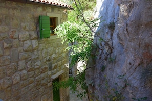 Ein Steinhaus mit einem grünen Fenster und einem schmalen Eingang.