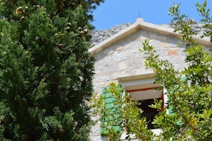 A stone building with a sloped roof, a window with green shutters, and a tree in the foreground. - Rustic, Modern Villa with pool (Omis)