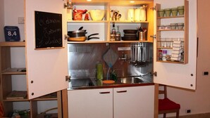 Una cucina compatta con una lavagna, scaffali con utensili da cucina e un lavello.