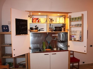 Eine kleine Küche mit einer Kreidetafel, Regalen mit Küchenutensilien und einem Spülbecken.