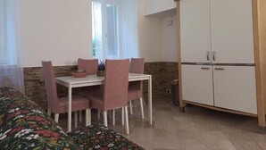 Una stanza arredata con un letto, un tavolo da pranzo con sedie, un armadio e una finestra con tende.