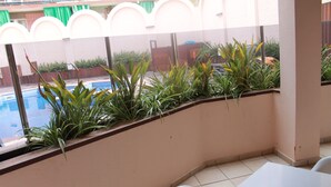 Uma varanda com piscina, plantas em vasos e uma mesa com cadeiras.