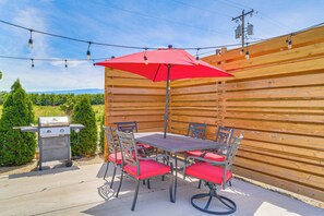 Une terrasse extérieure avec une table et des chaises, un barbecue et une clôture en bois.