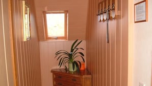 A narrow hallway with wooden paneling, a small window, a wooden cabinet with a plant, and a coat rack with hooks. - Maria Apartment 2 – Stay in the Heart of Wernigerode (Wernigerode)