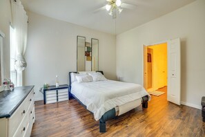 Ein Schlafzimmer mit Bett, Schminktisch, Nachttisch und Deckenventilator.