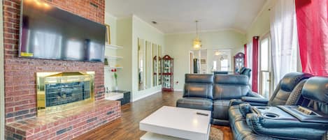 A living room with a brick fireplace, leather sofas, and a flat-screen TV.