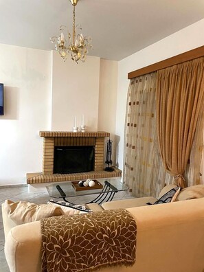Ein Wohnzimmer mit Kamin, einer Couch und Vorhängen.