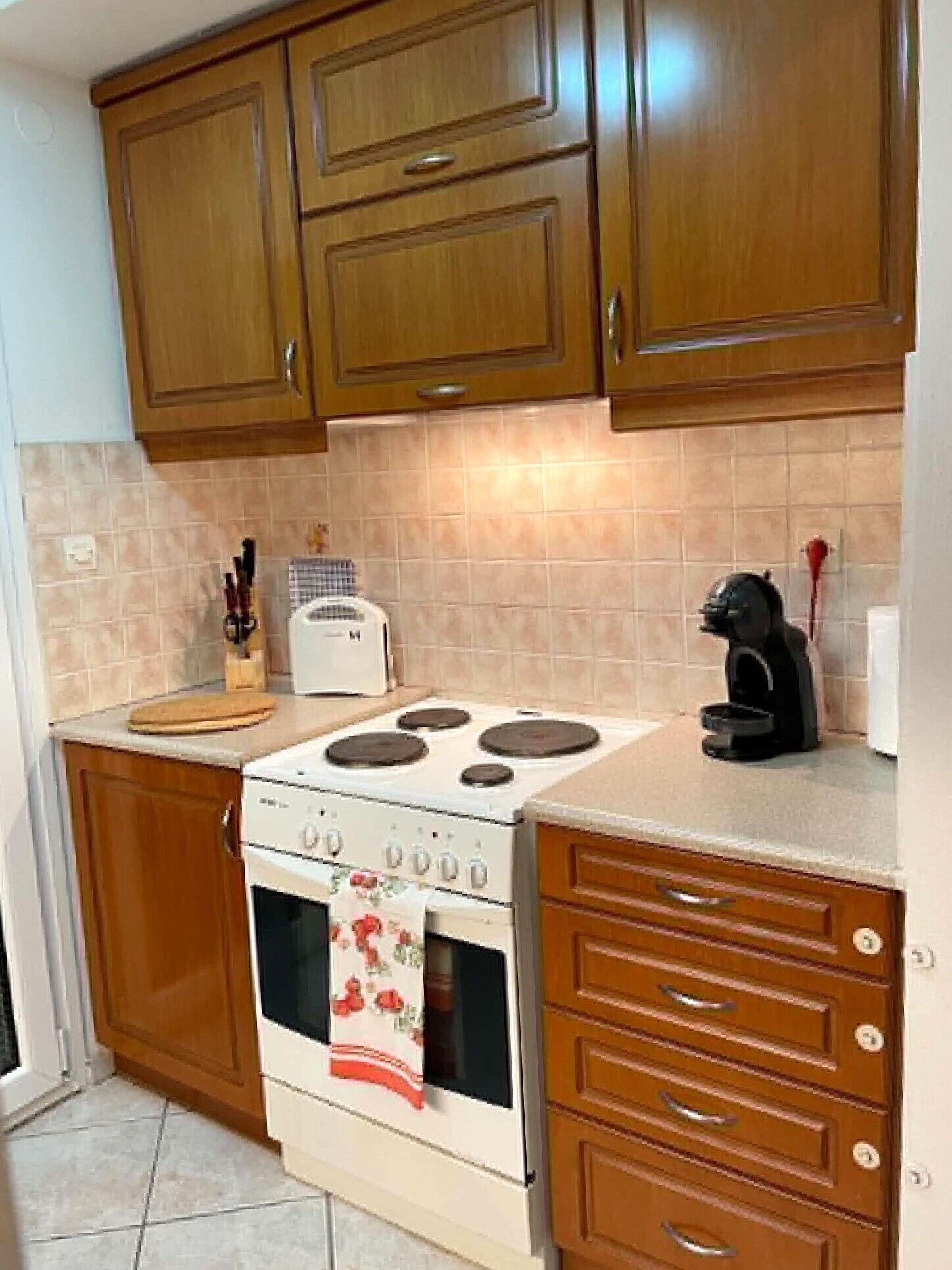 A kitchen with wooden cabinets, a stove, a toaster, and a coffee maker.