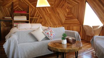 A cozy room with a wooden ceiling, a sofa, a round wooden table, and a small plant.