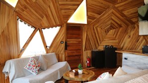A wooden interior with a sofa, a small table with a plant, and a fireplace. - Sama Tannourine Dome Houses (Tannourine El Faouqa)
