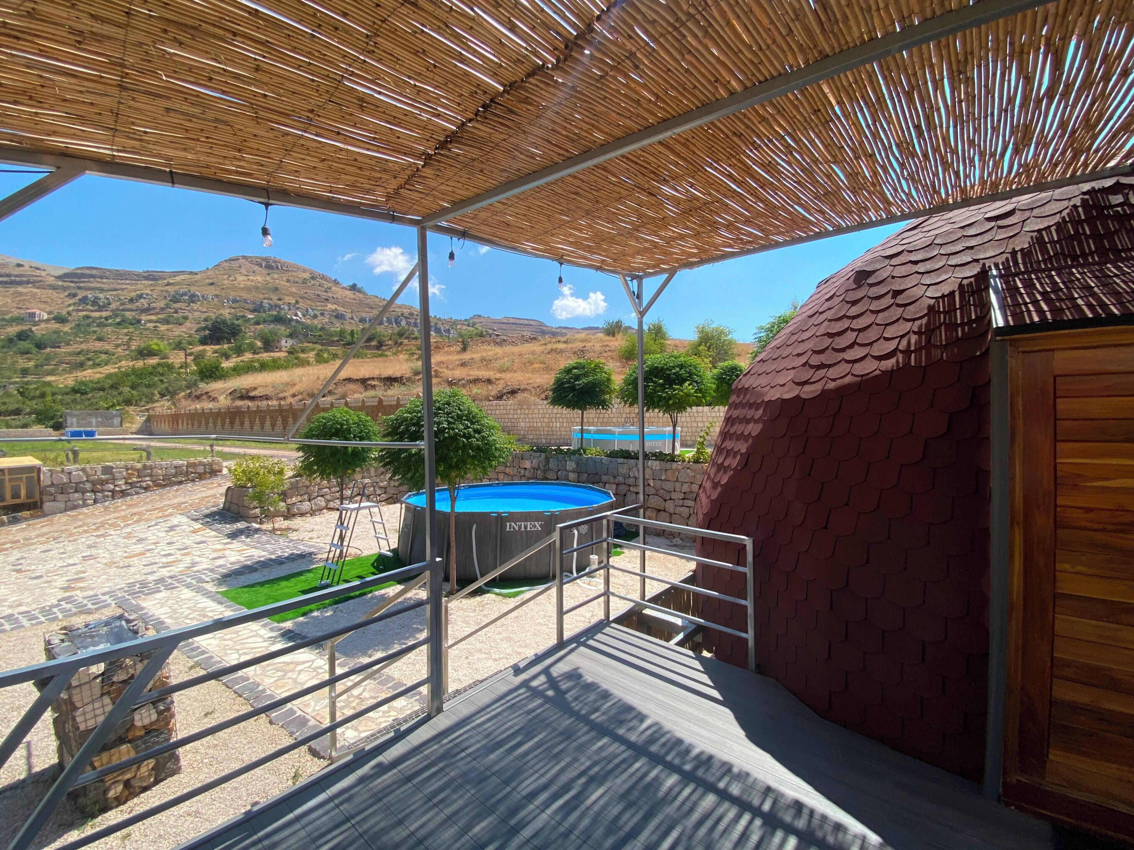 Un espacio al aire libre techado con piscina, una escalera y vistas del paisaje circundante.