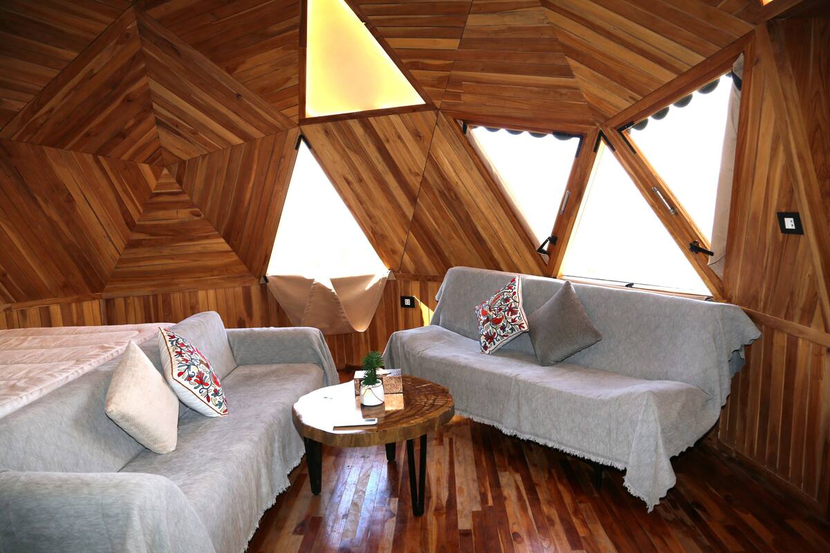 Una habitación acogedora con techo de madera, dos sofás, una mesa redonda y un ventanal.