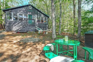 Une cabane avec un escalier menant à une terrasse, entourée d’arbres.
