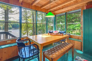 Un intérieur en bois, avec de grandes fenêtres, une table en bois, des chaises et un banc.