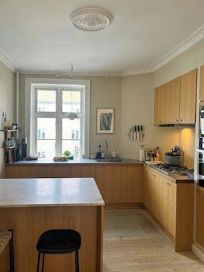 Eine Küche mit Holzausstattung, einer zentralen Kochinsel, einem Fenster mit Aussicht und einer hängenden Leuchte.