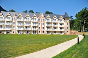 Een meerlaags hotel met een symmetrische gevel, balkons en een geplaveid pad ervoor.