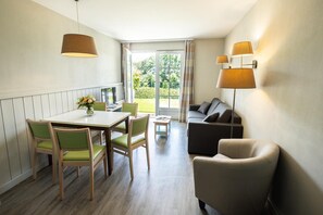 Een kamer met een eettafel, stoelen, een bank en een lamp.