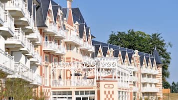 Een meerlaags hotel met balkons, een geruit patroon op de gevel en een heldere lucht.