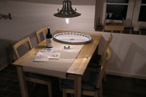 A dining table with a bottle, a plate, and papers on a tablecloth. - Holiday apartment in Nebel with swimming pool (Nebel)