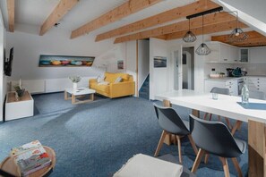 Ein modernes Interieur mit Essbereich, Küche und Wohnbereich, ausgestattet mit Holzbalken, einer Couch und einem Gemälde.