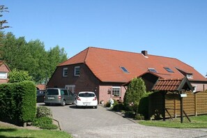 Ein Wohnhaus mit rotem Ziegeldach, einer Auffahrt und geparkten Autos.