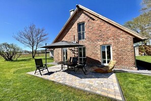 A brick house with a patio, outdoor seating, and a clear sky. - Holiday apartment with 1 bedroom (Versmold)