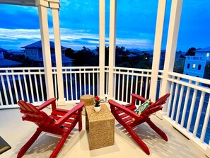 A balcony with two red Adirondack chairs and a small table, overlooking a residential area. - Balcony on Every Floor | Walk to Sand + Lagoon Pool | 30A Emerald Waters (Inlet Beach)