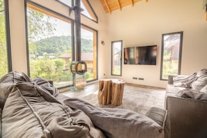 A modern living room with large windows, a fireplace, and a flat-screen TV. - Chalet Lignum, Sauna & SPA, Near Ski Slopes (La Bresse)