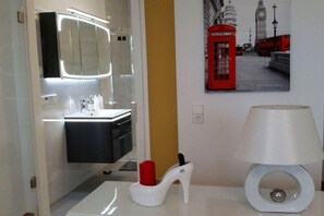 Casa de banho moderna com espelho, pia e uma decoração de cabine telefónica vermelha.