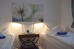 Ein Schlafzimmer mit zwei Betten, einem Nachttisch mit Lampe und einem an der Wand hängenden Kunstwerk.