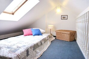 Ein Schlafzimmer mit einem Bett, einer Lampe, einem Korbwäsche und einem weißen Geländer.