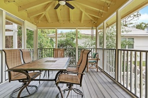 A covered patio with a table and chairs, wooden deck flooring, and a railing. - As You Like It | Steps to the Beach | Peek-a-boo Views (Santa Rosa Beach)