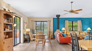 A spacious living room with a dining area, a fireplace, and large windows offering a view of the outdoors. - As You Like It | Steps to the Beach | Peek-a-boo Views (Santa Rosa Beach)