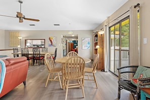 A spacious living area with a dining table, chairs, a sofa, and a balcony with a view. - As You Like It | Steps to the Beach | Peek-a-boo Views (Santa Rosa Beach)