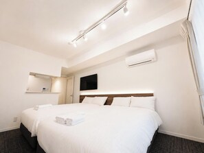 A hotel room with a bed, a TV, an air conditioning unit, and a window with curtains. - ONESATwin Room / Sapporo Hokkaidō (Sapporo)