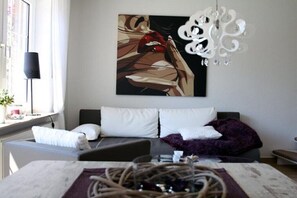 A modern living room with a sofa, a coffee table, and a painting on the wall. - Holiday home in Dornum with swimming pool (Dornum)