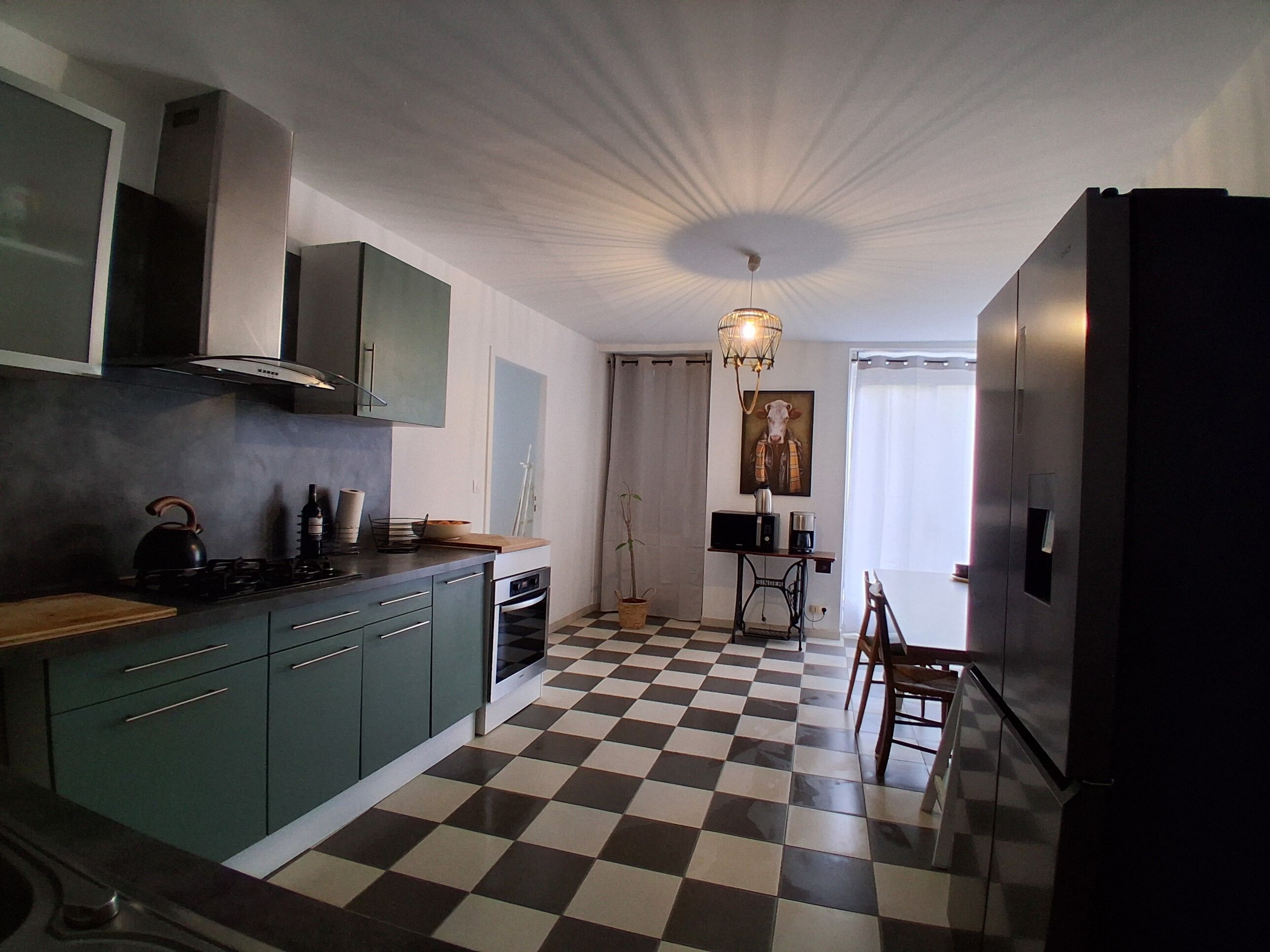 Una cucina con pavimento a scacchi, un piano cottura, pensili, un lavello e un'area pranzo con tavolo e sedie.