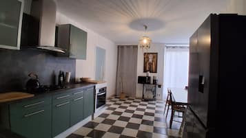Una cucina con pavimento a scacchi, un piano cottura, pensili, un lavello e un'area pranzo con tavolo e sedie.