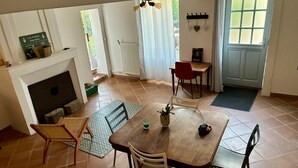 Ein Essbereich mit Tisch, Stühlen, einem Kamin und Blick ins Freie.