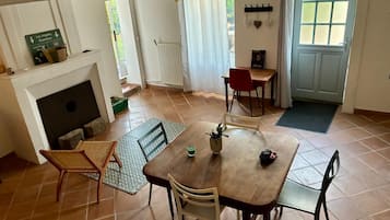 Zona pranzo con tavolo, sedie, camino e vista sull'esterno.