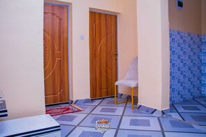 A room with two wooden doors, a white chair, and a patterned floor.