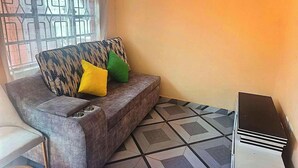 A corner room with a sofa, a chair, a radiator, and a patterned floor. - NAAMIN SPORTS LOUNGE KAGIO (Kagio)