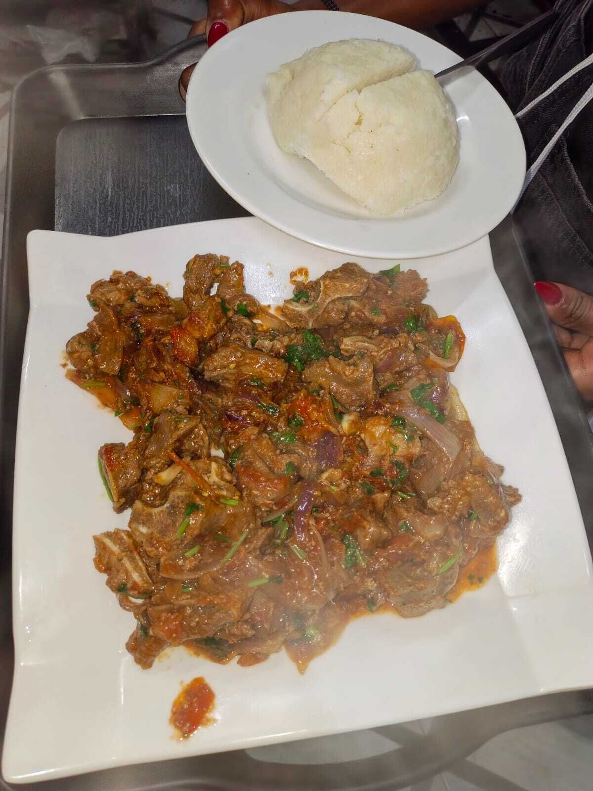 A plate of meat with sauce and a side of white rice.
