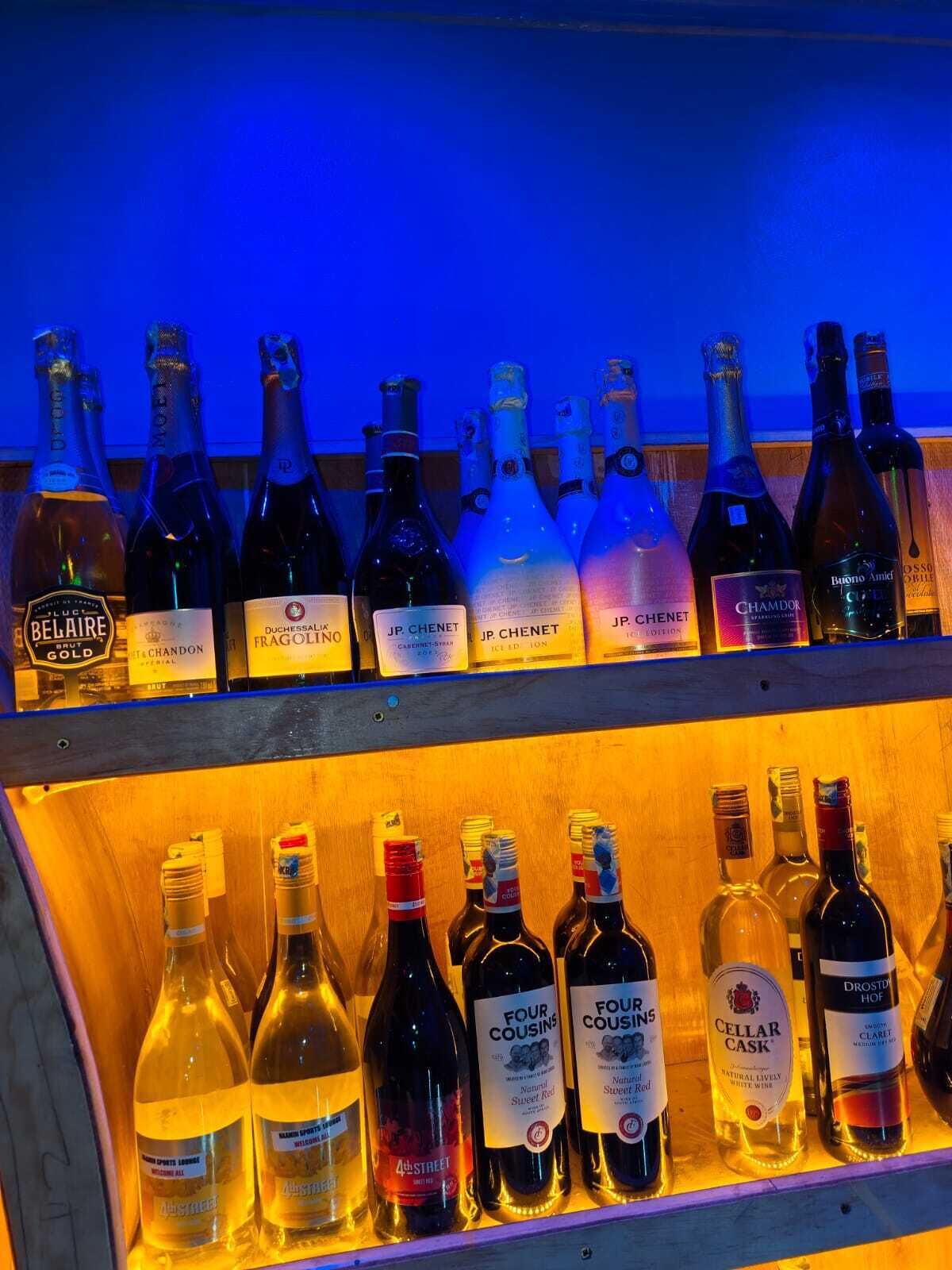 Eine Auswahl an Weinflaschen auf Regalen in einer Bar.