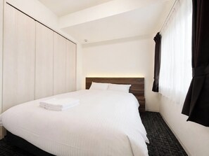 A hotel room with a bed, a wardrobe, a headboard, and a window with curtains. - ONESCLarge Twin Room / Sapporo Hokkaidō (Sapporo)
