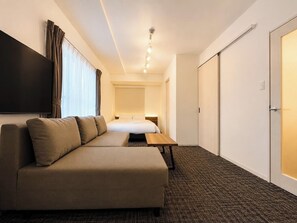 Ein Hotelzimmer mit einer Couch, einem Bett, einem Flachbildfernseher und einem Kleiderschrank.