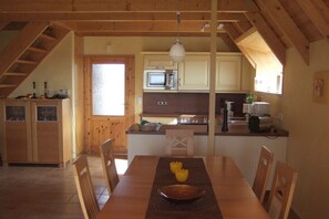 Eine Küche mit Holzschränken, einer Mikrowelle und einem Essbereich mit Tisch und Stühlen.